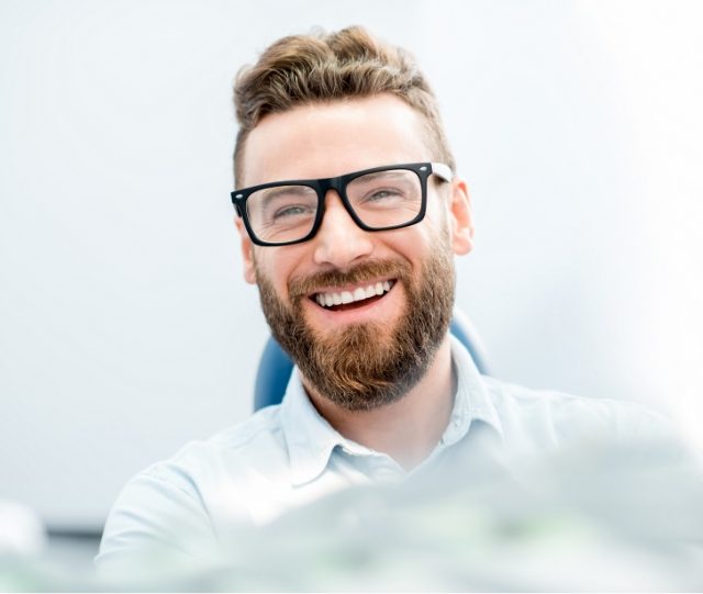 Man with glasses smiling in dental chair