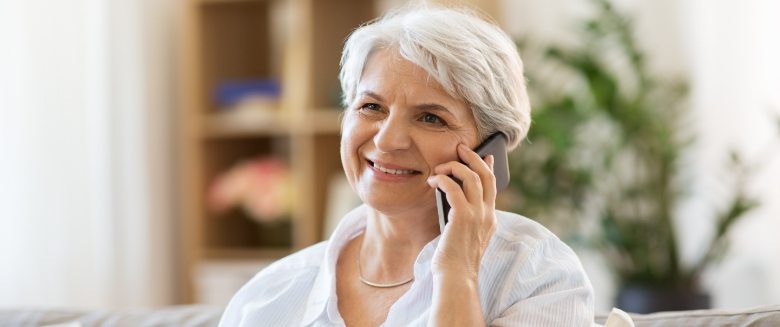 Senior woman sitting on couch and talking on phone