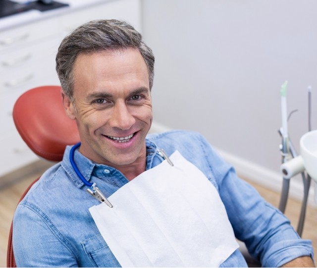 Male dental patient sitting in chair and smiling