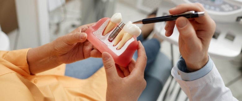 Showing a patient a model of a dental implant in Asheville