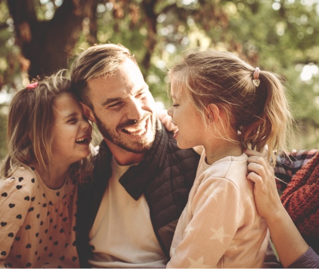 Man laughing with his two daughters