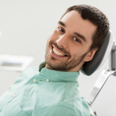 Bearded man sitting in dental chair and smiling