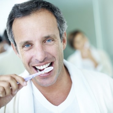 Man in white shirt brushing his teeth