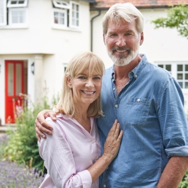 Man and woman standing outside house smiling