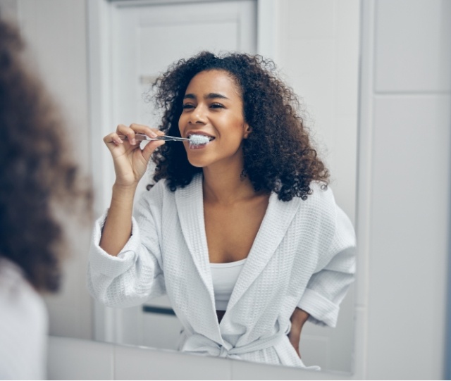 Woman in bathrobe brushing her teeth