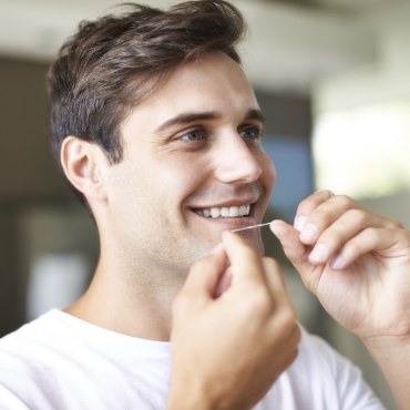 Man smiling and about to floss