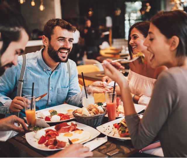 People sitting around table laughing and eating