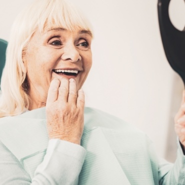 Senior woman looking at smile in handheld mirror