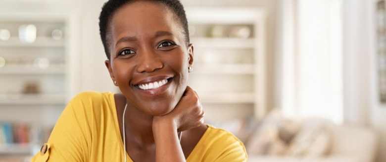 Woman in yellow shirt smiling at home