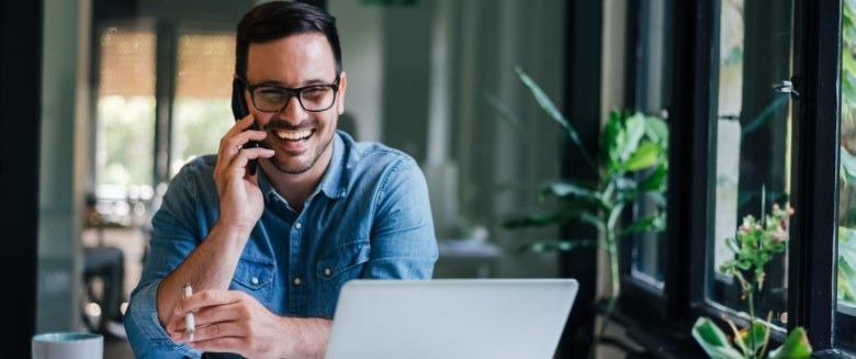 Man sitting at laptop and talking on phone