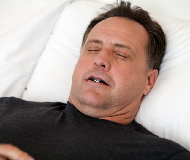 Man sleeping in bed wearing oral appliance