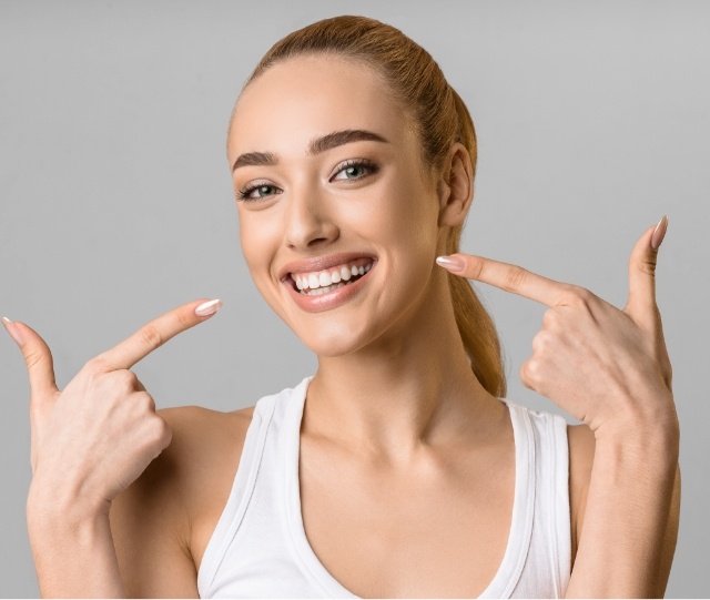 Woman smiling and pointing to her teeth