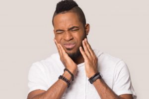 Man holding hands to jaw experiencing wisdom tooth pain