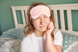 Woman with sleep mask rubs her toothache